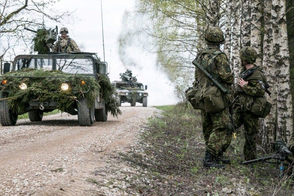 Soldados estonios observan como una columna de HMMWVs de la 173rd Airborne Brigade avanza por su posición durante el ejercicio Siil. Imagen - US Army - Sgt. 1st Class Joshua Brandenburg.